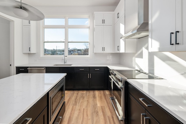 107 E 9th St Unit D7, Columbia, TN 38401 - kitchen with appliances with stainless steel finishes, wall chimney exhaust hood, a sink, light wood finished floors, and white cabinets