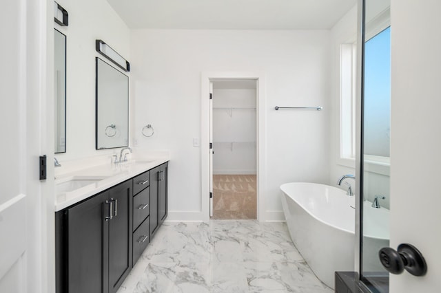 107 E 9th St Unit D7, Columbia, TN 38401 - bathroom featuring marble look tile flooring, a freestanding tub, double vanity, a spacious closet, and baseboards