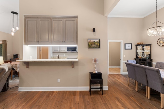 3006 Gracie Ann Dr, Greenbrier, TN 37073 - kitchen featuring open floor plan, a chandelier, a breakfast bar area, crown molding, and wood-type flooring