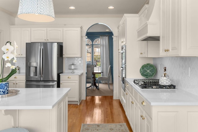 403 Butterfly Ct, Franklin, TN 37069 - kitchen with stainless steel appliances, premium range hood, arched walkways, decorative backsplash, and light countertops