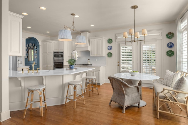 403 Butterfly Ct, Franklin, TN 37069 - kitchen featuring stainless steel double oven, a chandelier, a sink, a kitchen breakfast bar, and white cabinetry