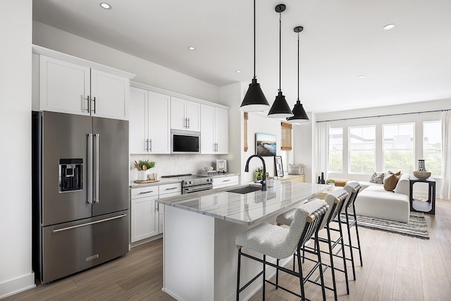 336 Hutcherson Aly, Nashville, TN 37209 - kitchen with stainless steel appliances, a sink, light wood finished floors, a kitchen island with sink, and light stone counters