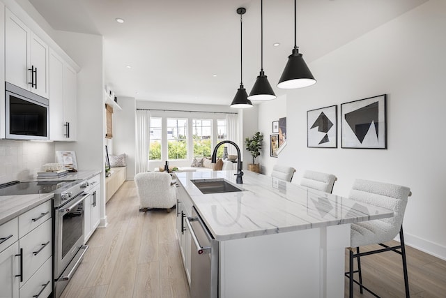 336 Hutcherson Aly, Nashville, TN 37209 - kitchen with a sink, stainless steel appliances, open floor plan, a breakfast bar, and recessed lighting