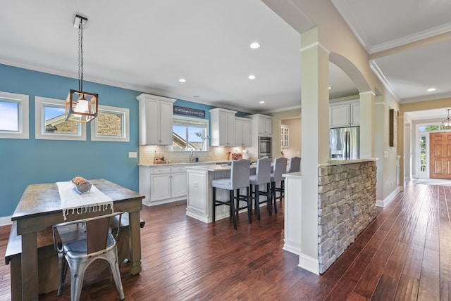 6740 Falls Ridge Ln, College Grove, TN 37046 - kitchen featuring a kitchen bar, stainless steel refrigerator with ice dispenser, white cabinets, crown molding, and decorative backsplash