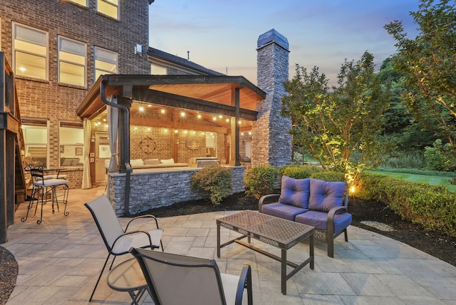 6740 Falls Ridge Ln, College Grove, TN 37046 - patio terrace at dusk featuring an outdoor living space, a patio area, an outdoor kitchen, and an outdoor bar