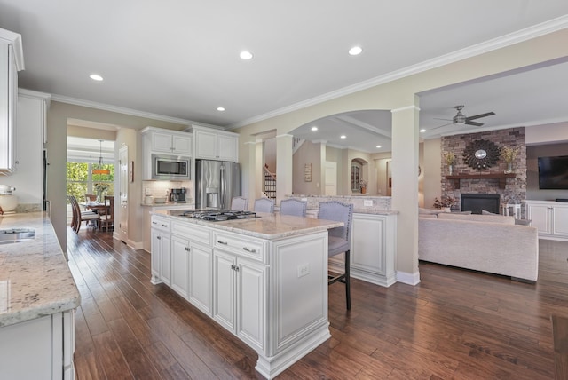 6740 Falls Ridge Ln, College Grove, TN 37046 - kitchen with appliances with stainless steel finishes, a ceiling fan, decorative columns, a fireplace, and white cabinetry