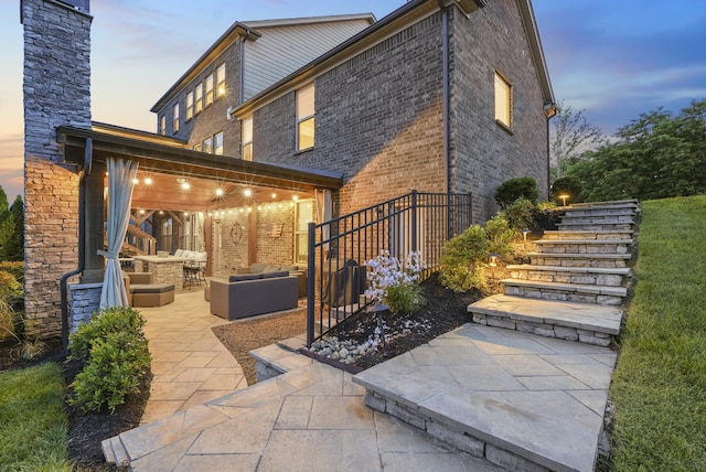 6740 Falls Ridge Ln, College Grove, TN 37046 - back of property at dusk featuring an outdoor living space, a patio, stairs, and brick siding