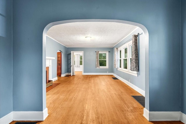 412 Cumberland St E, Cowan, TN 37318 - unfurnished room with arched walkways, light wood finished floors, a textured ceiling, a fireplace, and ornamental molding