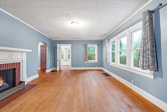 412 Cumberland St E, Cowan, TN 37318 - unfurnished living room with crown molding, wood finished floors, a fireplace, arched walkways, and a textured ceiling