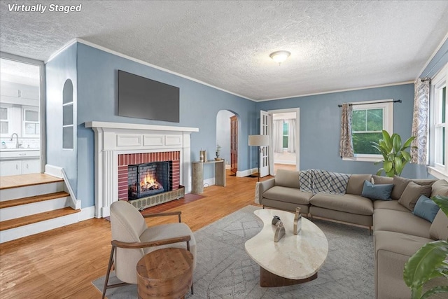 412 Cumberland St E, Cowan, TN 37318 - living area with a textured ceiling, crown molding, wood finished floors, arched walkways, and a brick fireplace