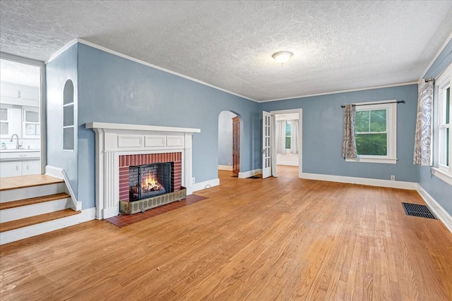 412 Cumberland St E, Cowan, TN 37318 - unfurnished living room featuring a textured ceiling, a fireplace, ornamental molding, wood finished floors, and arched walkways