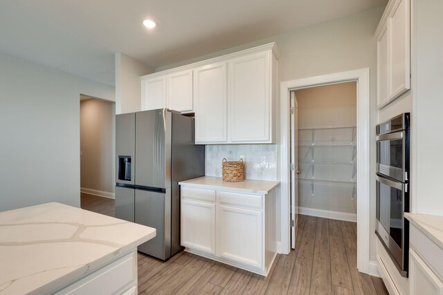 1207 Bridgett Way, Mount Juliet, TN 37122 - kitchen with appliances with stainless steel finishes, white cabinets, light wood-type flooring, light stone counters, and recessed lighting