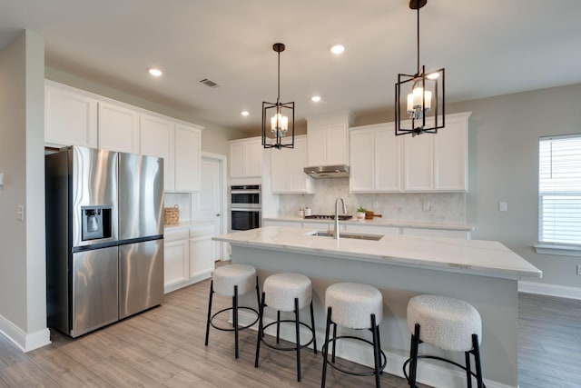 1207 Bridgett Way, Mount Juliet, TN 37122 - kitchen with appliances with stainless steel finishes, a sink, under cabinet range hood, light wood-type flooring, and decorative backsplash