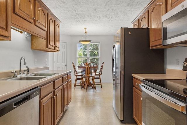 2707 Comer Dr, Murfreesboro, TN 37128 - kitchen featuring appliances with stainless steel finishes, a sink, brown cabinets, light countertops, and a textured ceiling