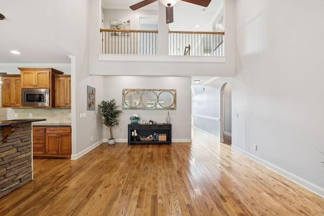 4181 Miles Johnson Pkwy, Spring Hill, TN 37174 - living room featuring ceiling fan, a towering ceiling, light wood-style flooring, arched walkways, and baseboards