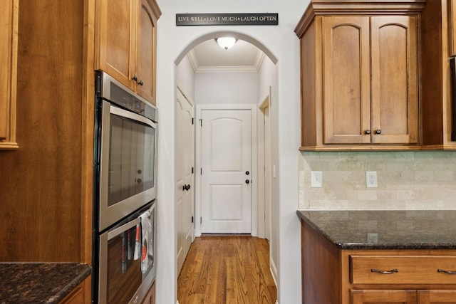 4181 Miles Johnson Pkwy, Spring Hill, TN 37174 - kitchen featuring crown molding, arched walkways, stainless steel double oven, wood finished floors, and backsplash