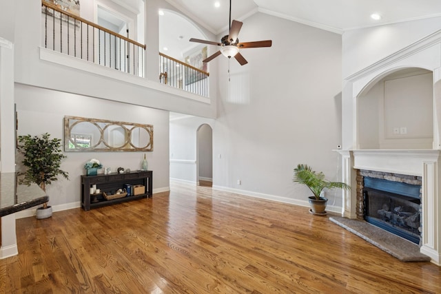 4181 Miles Johnson Pkwy, Spring Hill, TN 37174 - unfurnished living room with arched walkways, a ceiling fan, high vaulted ceiling, a stone fireplace, and wood finished floors