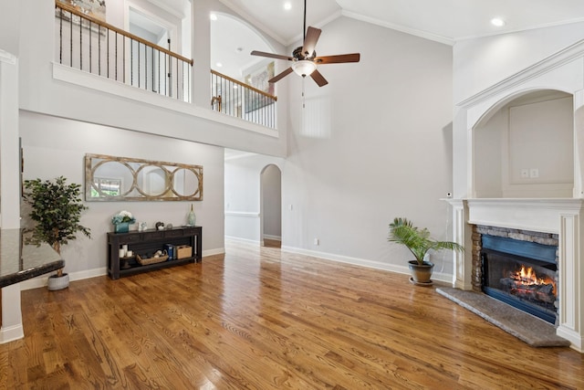 4181 Miles Johnson Pkwy, Spring Hill, TN 37174 - unfurnished living room featuring arched walkways, a ceiling fan, a stone fireplace, high vaulted ceiling, and wood finished floors