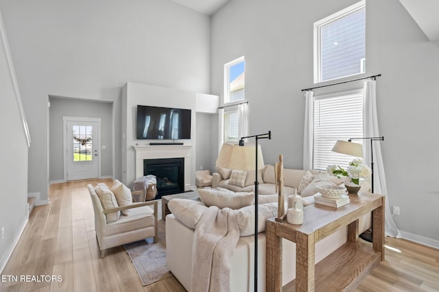 324 Gulfstream Dr, Gallatin, TN 37066 - living room featuring a towering ceiling, a glass covered fireplace, baseboards, and light wood-type flooring