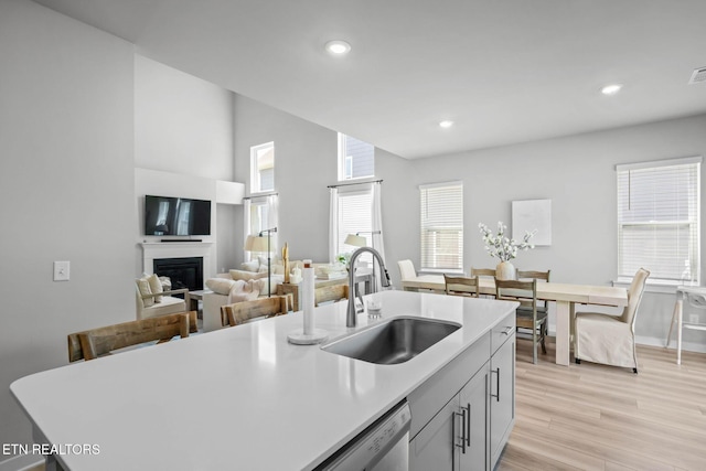 324 Gulfstream Dr, Gallatin, TN 37066 - kitchen featuring a sink, light countertops, a glass covered fireplace, light wood finished floors, and recessed lighting