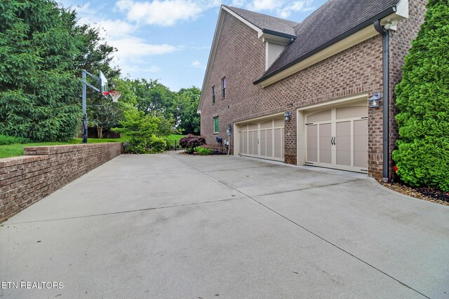 550 Stone Villa Ln, Knoxville, TN 37934 - view of property exterior with driveway, brick siding, an attached garage, and a shingled roof