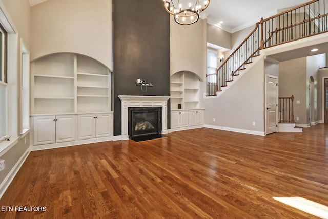 550 Stone Villa Ln, Knoxville, TN 37934 - unfurnished living room with a high ceiling, built in shelves, baseboards, a chandelier, and wood finished floors