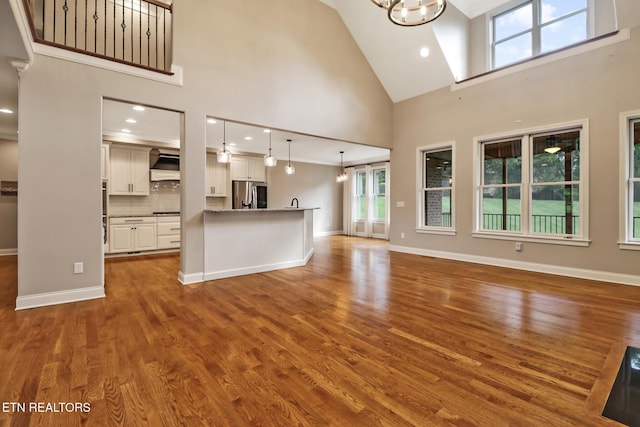 550 Stone Villa Ln, Knoxville, TN 37934 - unfurnished living room with high vaulted ceiling, dark wood-style floors, a chandelier, baseboards, and recessed lighting