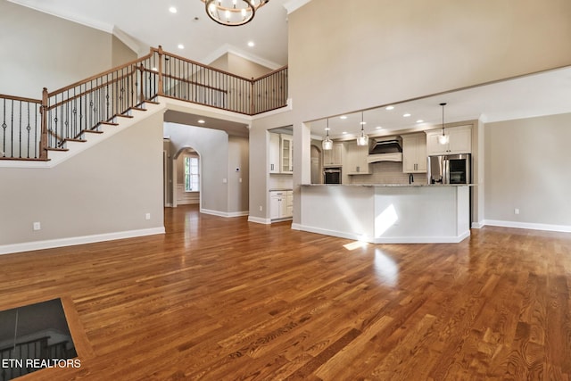 550 Stone Villa Ln, Knoxville, TN 37934 - unfurnished living room with crown molding, arched walkways, dark wood-type flooring, a high ceiling, and baseboards