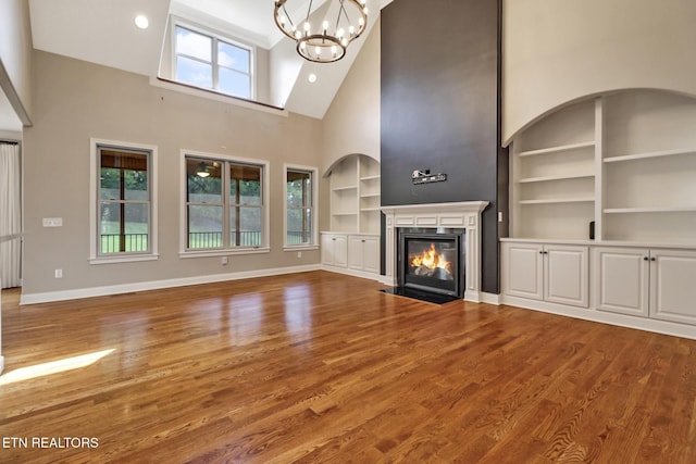 550 Stone Villa Ln, Knoxville, TN 37934 - unfurnished living room featuring built in shelves, high vaulted ceiling, a chandelier, a fireplace with flush hearth, and baseboards