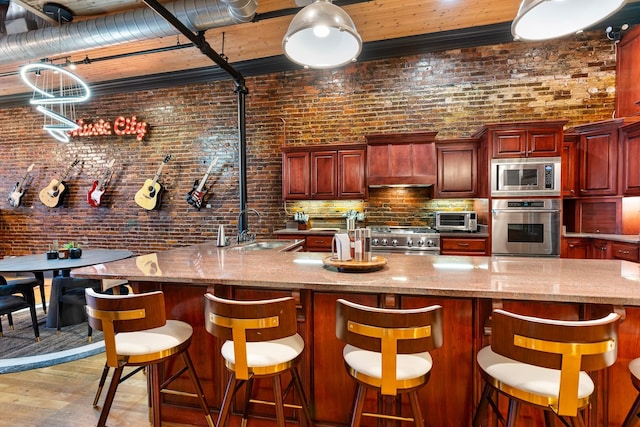 207 3rd Ave N Unit 602, Nashville, TN 37201 - kitchen with appliances with stainless steel finishes, a sink, reddish brown cabinets, custom range hood, and light wood-type flooring