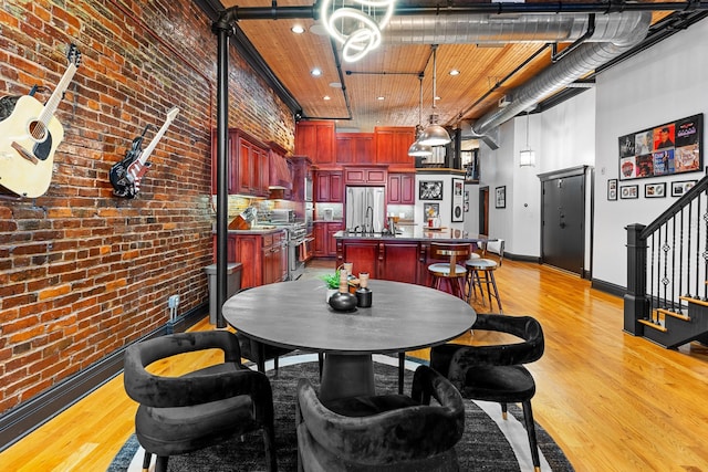 207 3rd Ave N Unit 602, Nashville, TN 37201 - dining room featuring light wood-style flooring, brick wall, stairway, baseboards, and recessed lighting