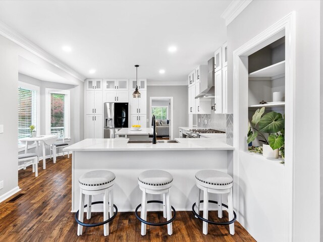 2207 Oakwood Ct, Franklin, TN 37064 - kitchen featuring stainless steel refrigerator with ice dispenser, a peninsula, wall chimney exhaust hood, white cabinetry, and crown molding