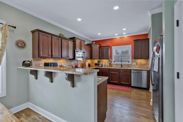 2122 Slater Dr, Murfreesboro, TN 37128 - kitchen with appliances with stainless steel finishes, a peninsula, a kitchen breakfast bar, wood finished floors, and decorative backsplash