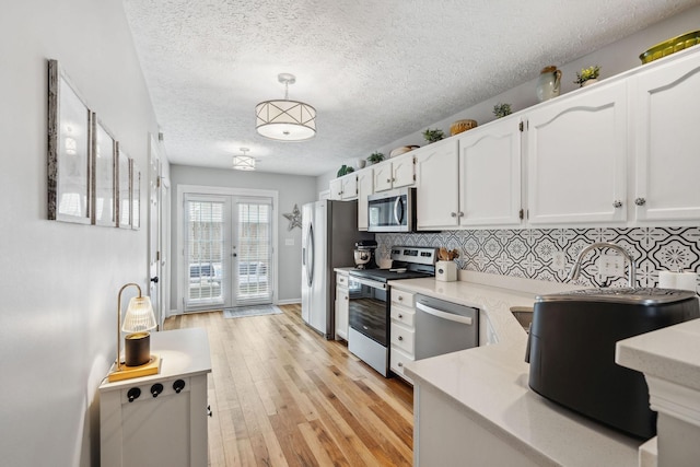 3207 Gardendale Dr, Franklin, TN 37064 - kitchen featuring stainless steel appliances, white cabinetry, backsplash, light countertops, and light wood finished floors