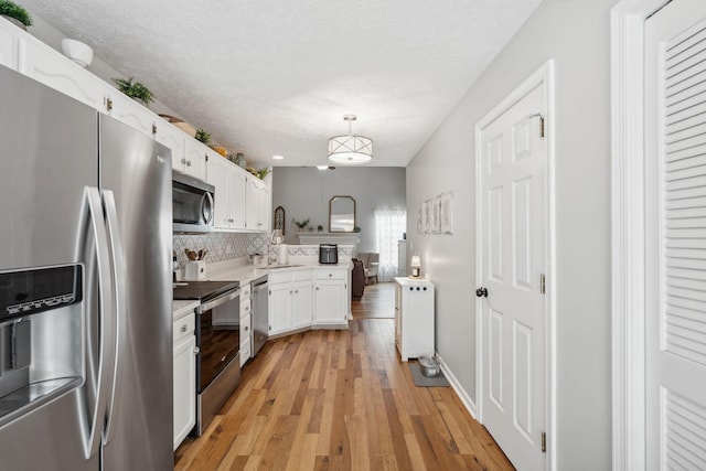 3207 Gardendale Dr, Franklin, TN 37064 - kitchen with appliances with stainless steel finishes, white cabinetry, light wood-style flooring, light countertops, and decorative backsplash