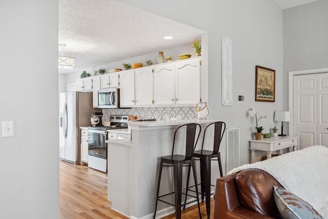 3207 Gardendale Dr, Franklin, TN 37064 - kitchen with stainless steel appliances, a kitchen breakfast bar, white cabinetry, a peninsula, and light wood finished floors