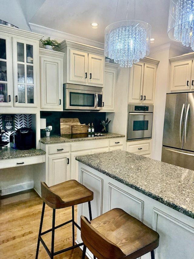 2815 Anglo Ct, Murfreesboro, TN 37129 - kitchen featuring stainless steel appliances, a chandelier, a breakfast bar, ornamental molding, and dark stone countertops