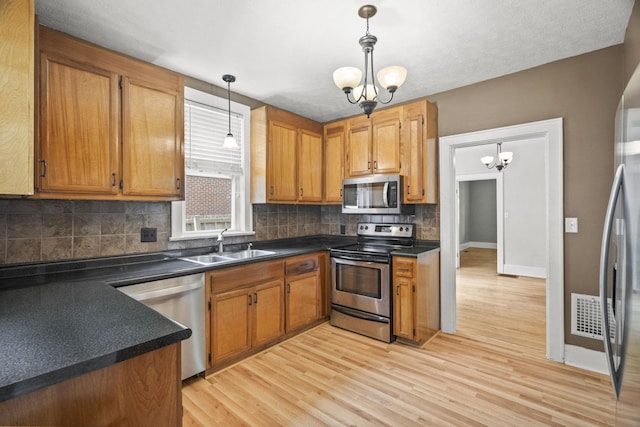 400 Connell St, Springfield, TN 37172 - kitchen with appliances with stainless steel finishes, a sink, dark countertops, light wood finished floors, and a chandelier