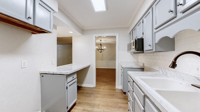 1280 Middle Tennessee Blvd Unit D6, Murfreesboro, TN 37130 - kitchen featuring a sink, light wood-type flooring, decorative backsplash, stainless steel microwave, and a chandelier