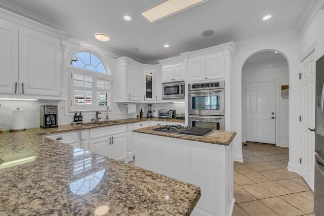 1918 Mosaic Trl, Murfreesboro, TN 37130 - kitchen featuring appliances with stainless steel finishes, a sink, arched walkways, white cabinetry, and crown molding