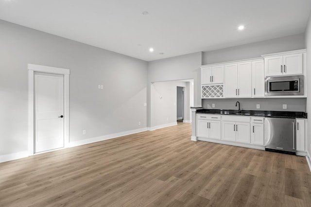 2736 Hartsville Pike, Castalian Springs, TN 37031 - kitchen featuring appliances with stainless steel finishes, dark countertops, light wood-style flooring, white cabinetry, and baseboards