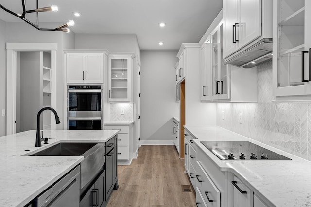 2736 Hartsville Pike, Castalian Springs, TN 37031 - kitchen featuring stainless steel double oven, black electric stovetop, white cabinets, light wood-style flooring, and backsplash