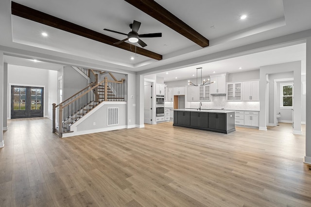 2736 Hartsville Pike, Castalian Springs, TN 37031 - unfurnished living room featuring a sink, baseboards, stairway, light wood-type flooring, and beamed ceiling