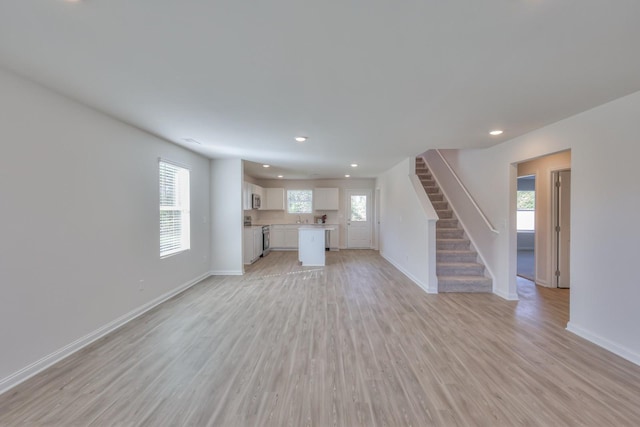 515 Cedar Brook Dr, White House, TN 37188 - unfurnished living room featuring stairway, baseboards, light wood-style flooring, recessed lighting, and a sink