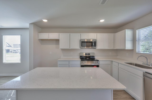 515 Cedar Brook Dr, White House, TN 37188 - kitchen featuring stainless steel appliances, a sink, a kitchen island, light wood-style flooring, and light stone counters