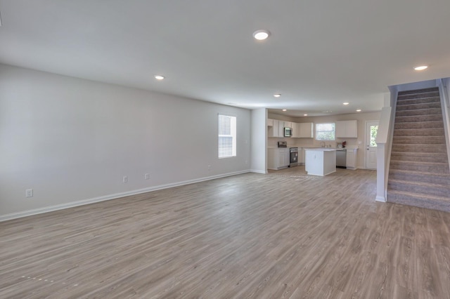 515 Cedar Brook Dr, White House, TN 37188 - unfurnished living room featuring recessed lighting, stairs, light wood finished floors, baseboards, and a sink