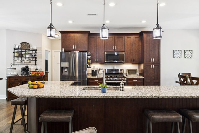 121 Regency Ln, Dickson, TN 37055 - kitchen with appliances with stainless steel finishes, a sink, dark wood finished floors, a breakfast bar, and hanging light fixtures