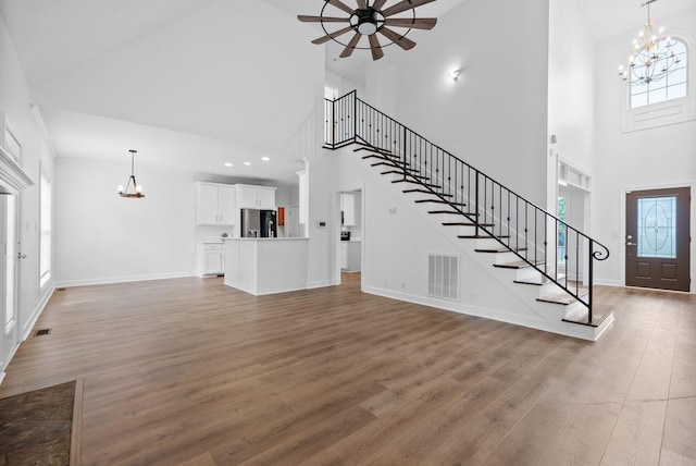3692 Prestwicke Pl, Adams, TN 37010 - unfurnished living room featuring a chandelier, high vaulted ceiling, stairs, ceiling fan, and wood finished floors