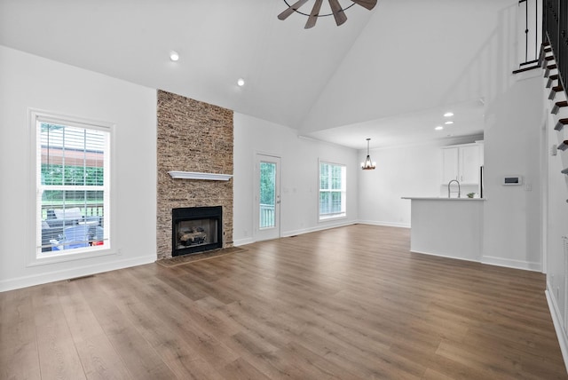 3692 Prestwicke Pl, Adams, TN 37010 - unfurnished living room with high vaulted ceiling, a fireplace, wood finished floors, a ceiling fan, and a chandelier