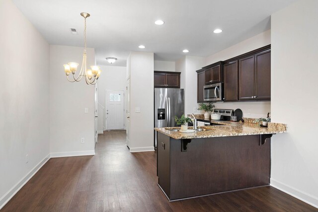 1710 Lone Jack Ln, Murfreesboro, TN 37129 - kitchen with appliances with stainless steel finishes, a peninsula, dark brown cabinetry, a kitchen breakfast bar, and light stone countertops